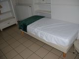 a small bed with a green blanket in a small room