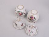 four pieces of porcelain with floral designs on them sitting on a table