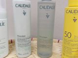 three bottles of caudalie lotion sitting on top of a woven basket