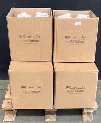Plusieurs cartons sont empilés sur des palettes devant un mur noir.