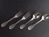 four spoons and a fork are lined up on a black surface