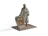 figurine of a man standing on a rug with a suitcase