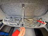 a person holding a wrench and a wrench in a car trunk