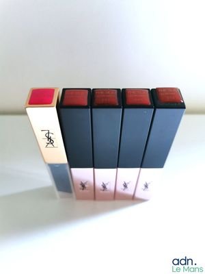 quatre rouges à lèvres sont alignés sur une surface blanche