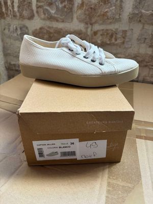white sneakers with white laces are on top of a cardboard box