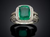 an emerald and diamond ring on a black surface