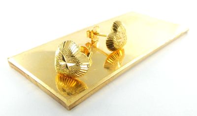 a picture of a pair of earrings that are on a gold plate
