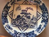 a blue and white plate with a picture of a landscape on it
