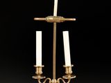 an antique brass candelab with three candles on a red table