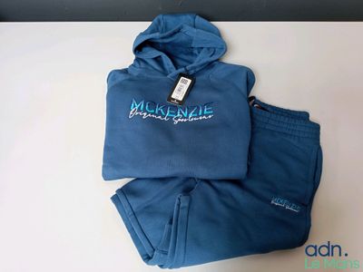 Le sweat à capuche bleu et le pantalon sont posés sur une table blanche.