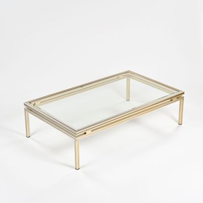 une table basse en verre et en laiton sur fond blanc