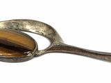 silver spoon with a tiger ' s eye on it on a white surface