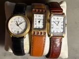 trois montres de couleurs différentes exposées sur un présentoir blanc