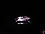 a close up of a purple and white diamond on a black surface
