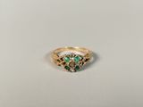 a close up of a gold ring with green stones