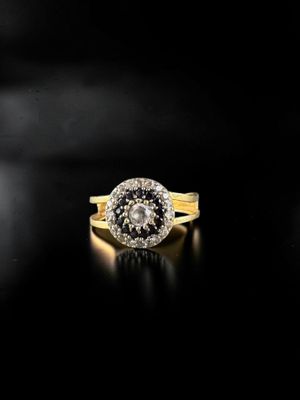 a close up of a gold ring with a black and white diamond center