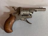un vieux pistolet avec une poignée en bois sur une surface blanche