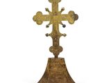 une croix en or posée sur un socle en bois, sur fond blanc