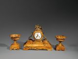 une petite horloge et deux petites bougies posées sur une table