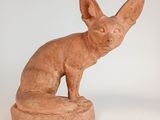 sculpture représentant un chat assis sur un rocher, posée sur une surface blanche