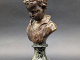 a bronze bust of a woman with a hat on top of a pedestal