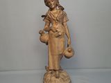 statue d'une femme tenant un oiseau et un pot, posée sur un socle