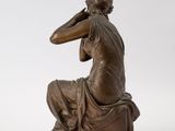 a bronze statue of a man sitting on a rock with his hand on his head