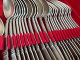a lot of silver spoons and spoons on a red cloth