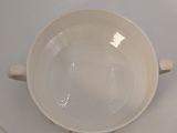 a white bowl sitting on a table next to a plate with a red and black design