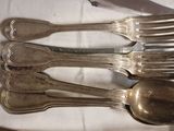 five silver spoons and two silver spoons on a table