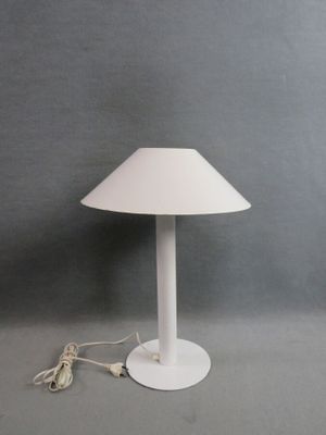 une lampe de table blanche posée sur une table près d'un mur gris