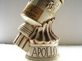 une petite statue représentant un robot tenant une canette d'Apollo