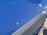 a close up of a blue car with a person standing next to it