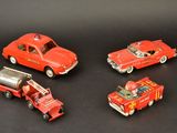 four toy cars and a fire truck on a black surface