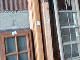 une échelle appuyée contre un mur, à côté d'un tas de vieilles fenêtres