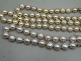 three strands of white pearls with gold clasps on a white surface