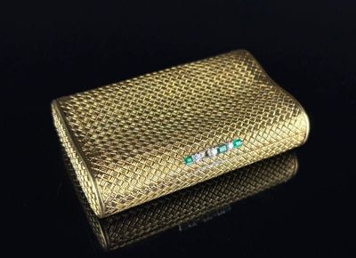 un étui à cigarettes en or, orné d'émeraudes et de diamants sur un fond noir