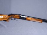 un fusil de chasse posé sur une table, sur lequel est posé un chapeau