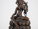 une statue en bronze représentant une femme assise sur une table