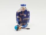 a small blue glass bottle with a wooden stopper next to it