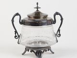 an antique silver plated teapot with a glass lid on a stand