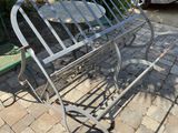 a metal bench sitting on a brick patio next to a table