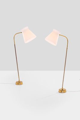 a pair of brass floor lamps with white shades