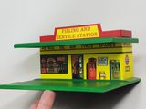 a hand that is holding a small model of a gas station