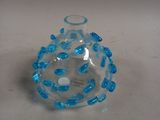 a glass vase with blue beads on it on a table
