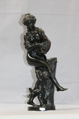statue en bronze représentant une femme assise sur un rocher avec un chien