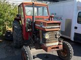 a red tractor that is parked next to a white truck