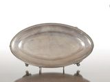 un plateau d'argent antique sur un support sur une surface blanche
