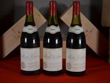 three bottles of red wine sit on a red table cloth