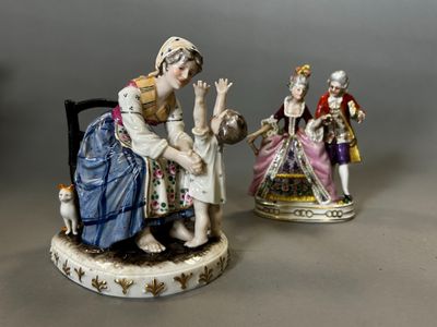 two figurines of women and a cat are sitting on a chair